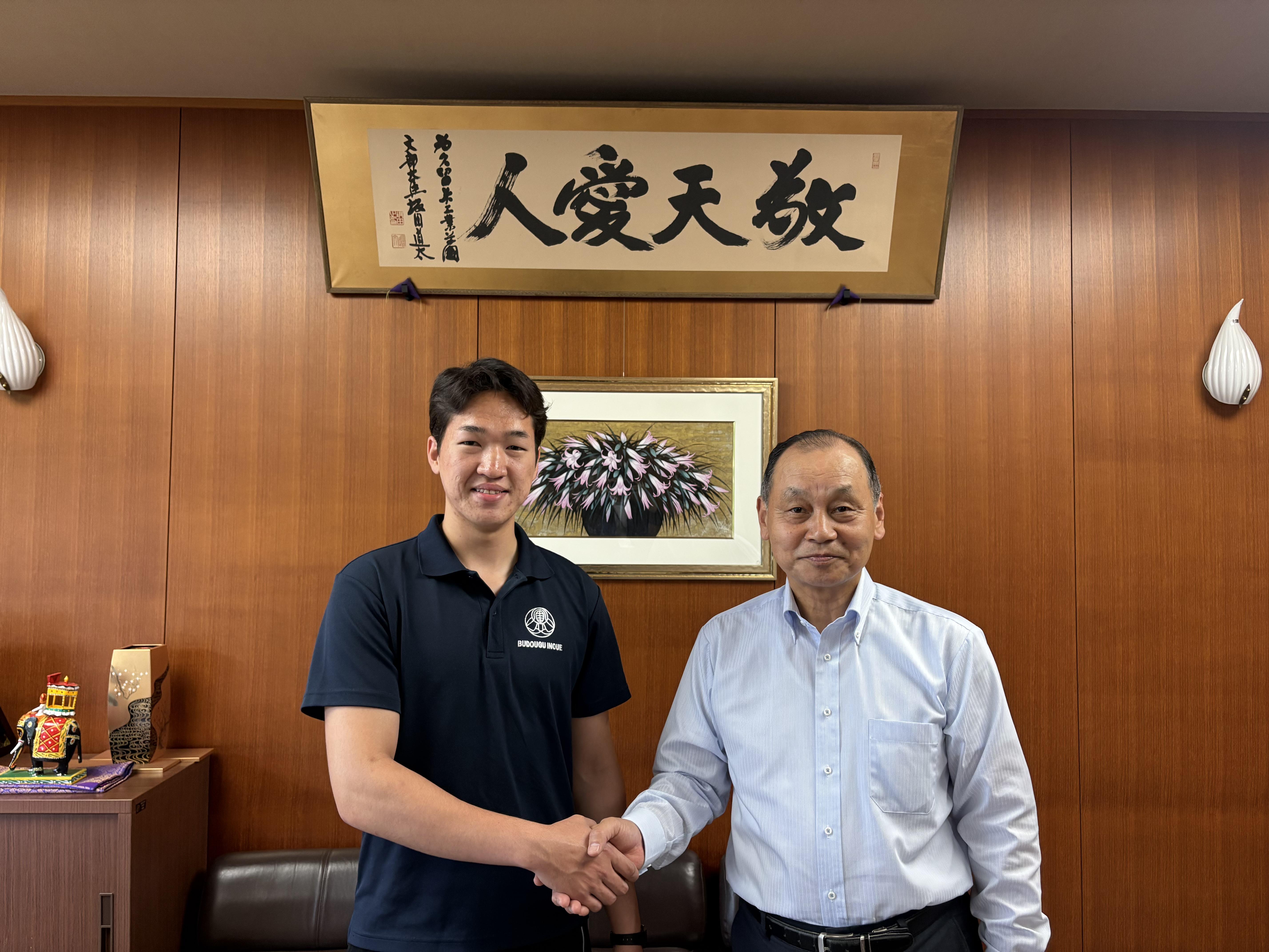 第1回アジア・オセアニア剣道選手権大会での健闘を誓い、久留米工業大学の日野伸一学長と力強く握手を交わすイヘバヤルさん
