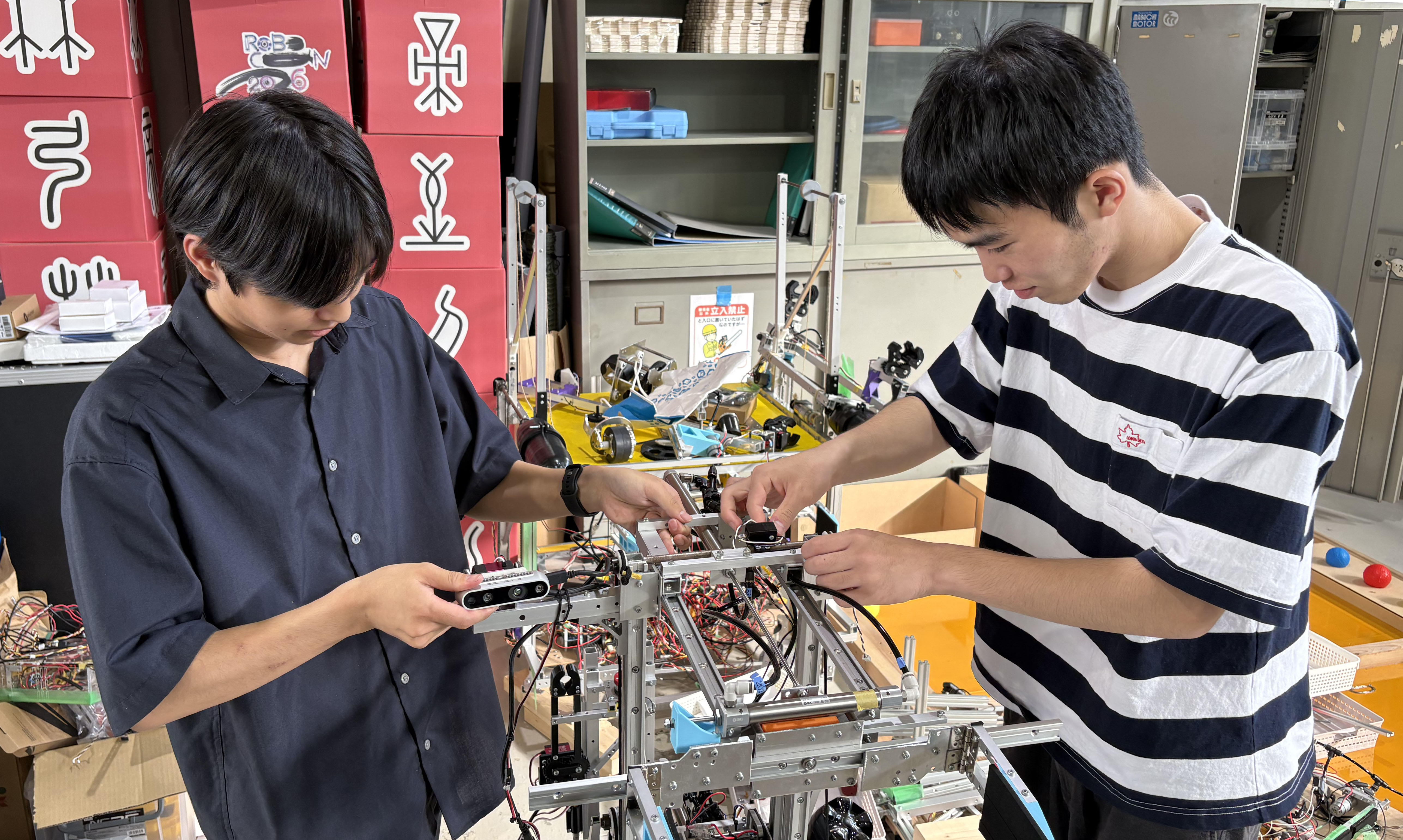 九州夏ロボコン優勝に向けて熱い想いとポーズを見せる久留米工業大学の髙木さんと平嶋さん