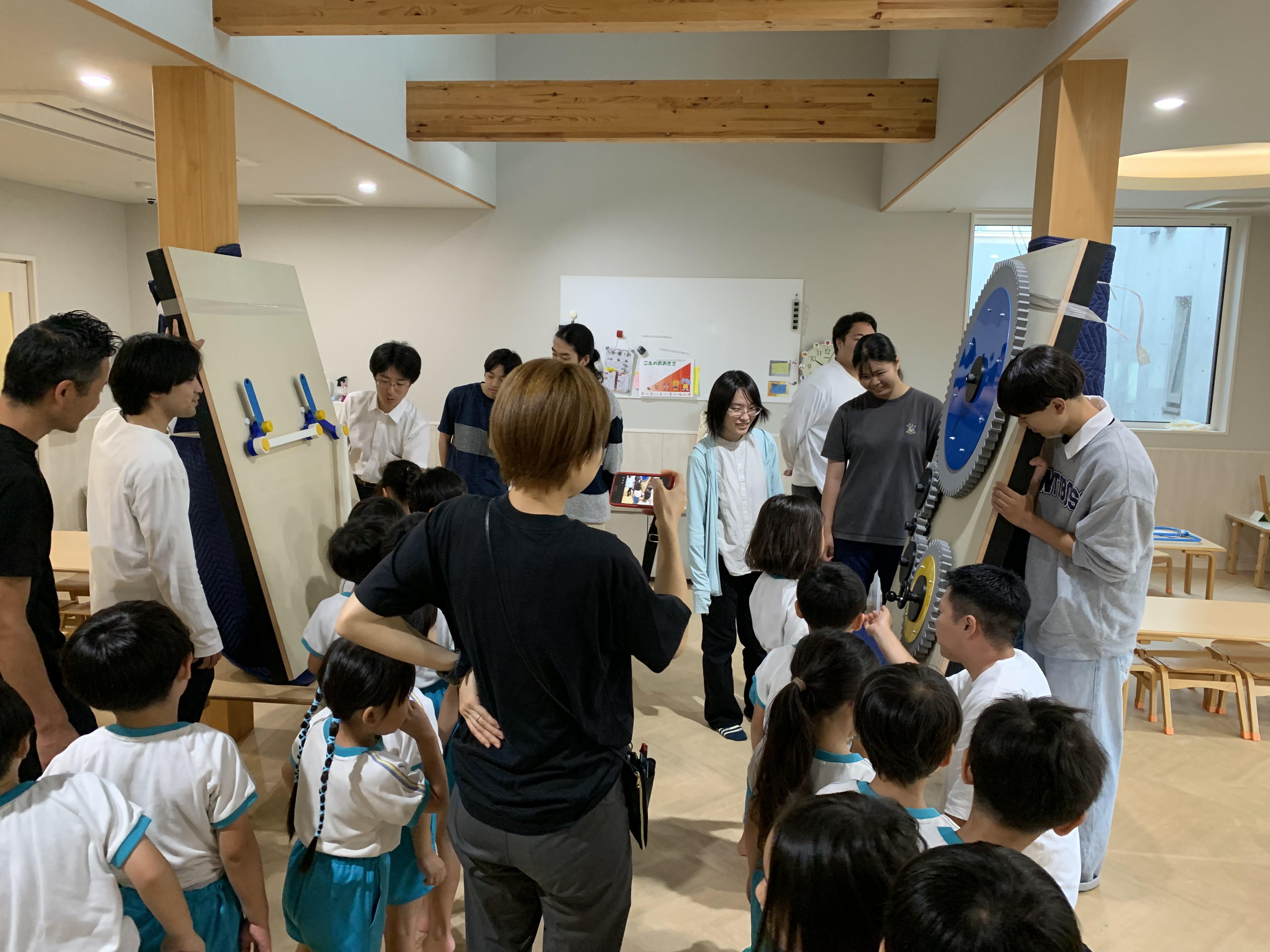 装置の横に取り付けられた丸いハンドルに手をかけ、夢中になってぐるぐると回して遊ぶ園児の様子。