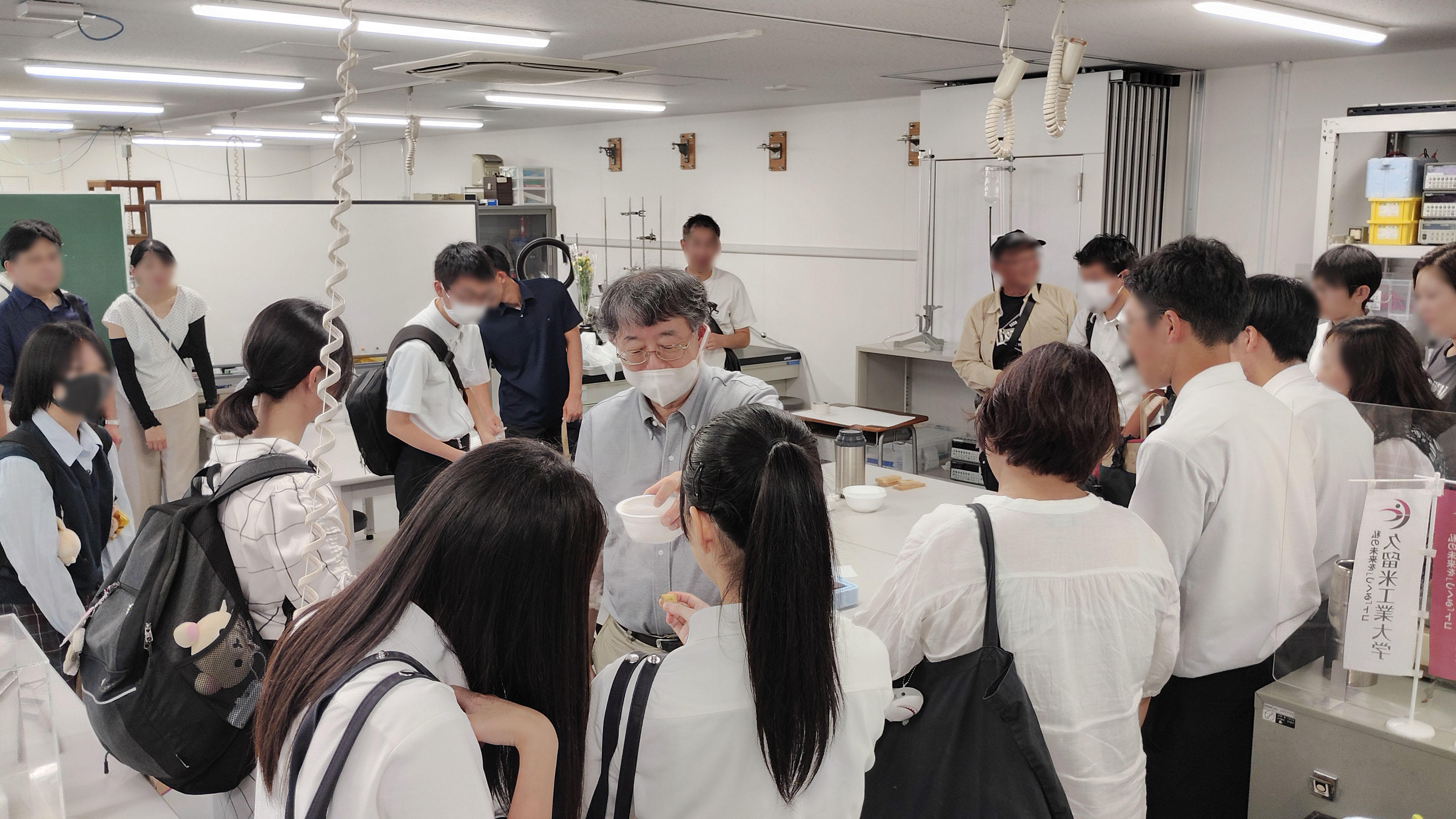久留米工業大学の夏のオープンキャンパスで、各学科の実験設備や最先端テクノロジーに触れて体験実験会を楽しむ参加者の様子