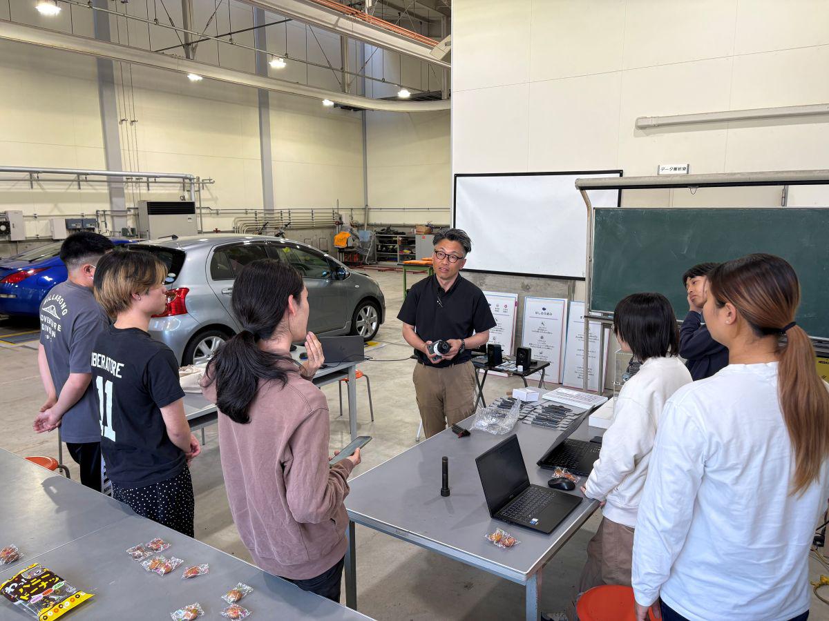 久留米工業大学の異なる学科から集まった学生たちと梶山助教が、円になって活発に意見を交換し、学科横断のコラボレーションを進めている場面