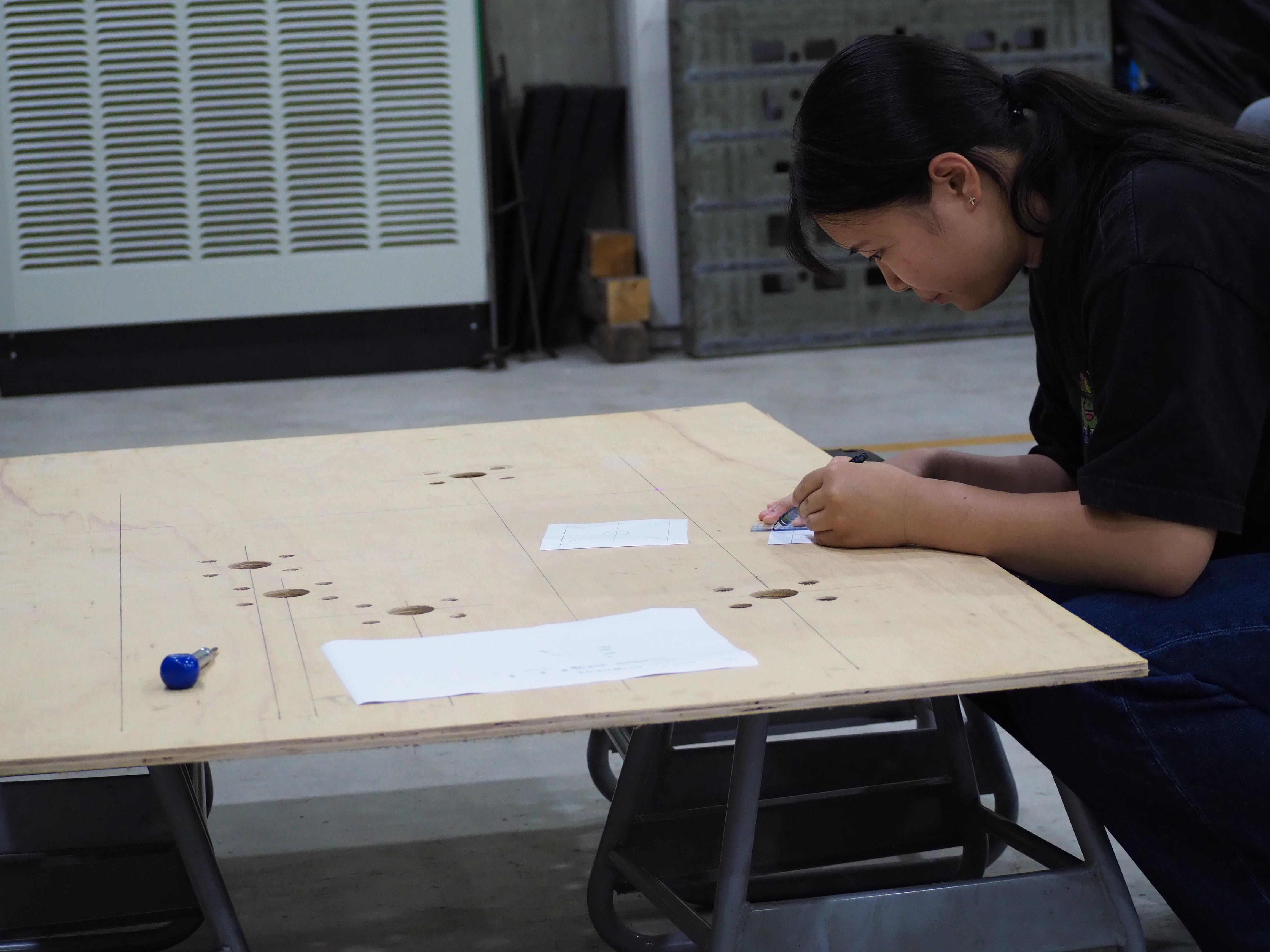 久留米工業大学の学生が、小学校低学年向けの展示物解説パネルの制作にひとりでものづくりに取り組む様子
