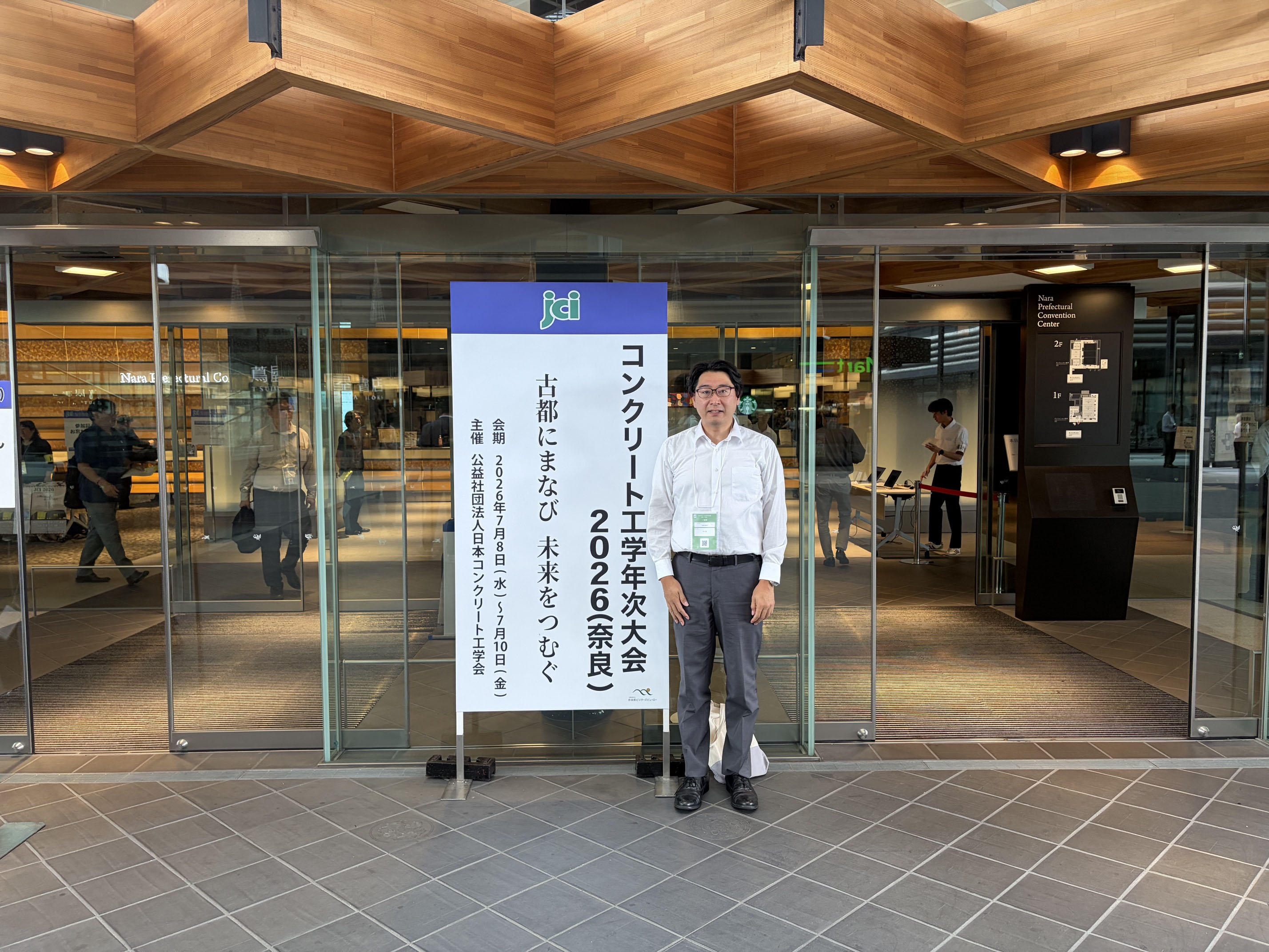 コンクリート工学年次大会2026の会場(奈良コンベンションセンター)エントランスで記念撮影をする久留米工業大学の松本豊教授