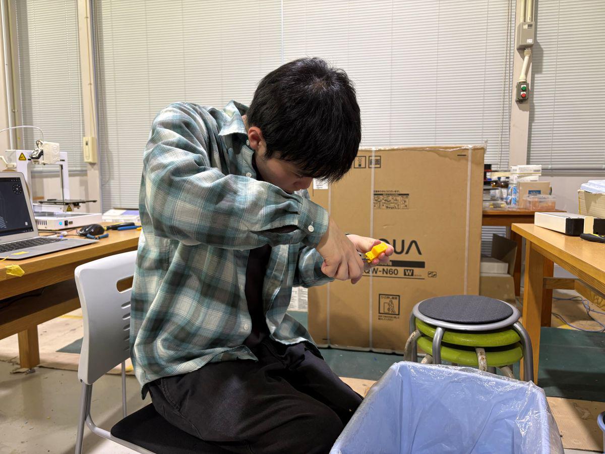 久留米工業大学のものづくりセンターにて、3Dプリンターで作成したロボット部品を真剣な表情で削り、微調整を行う平嶋さん